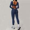 Woman wearing navy blue open-back summer jumpsuit with long sleeves and full-length legs.