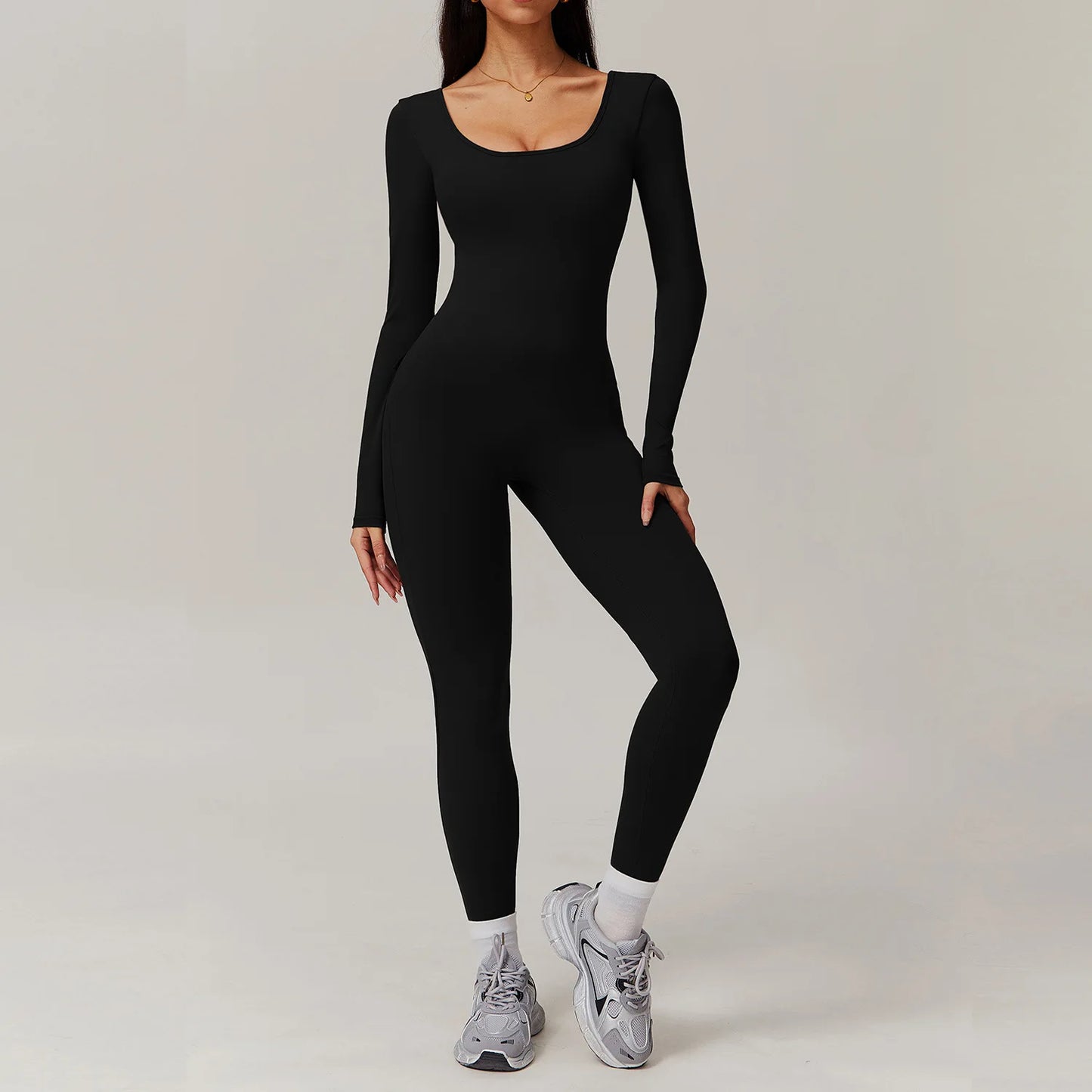 Woman wearing black open-back summer jumpsuit with long sleeves and full-length legs.