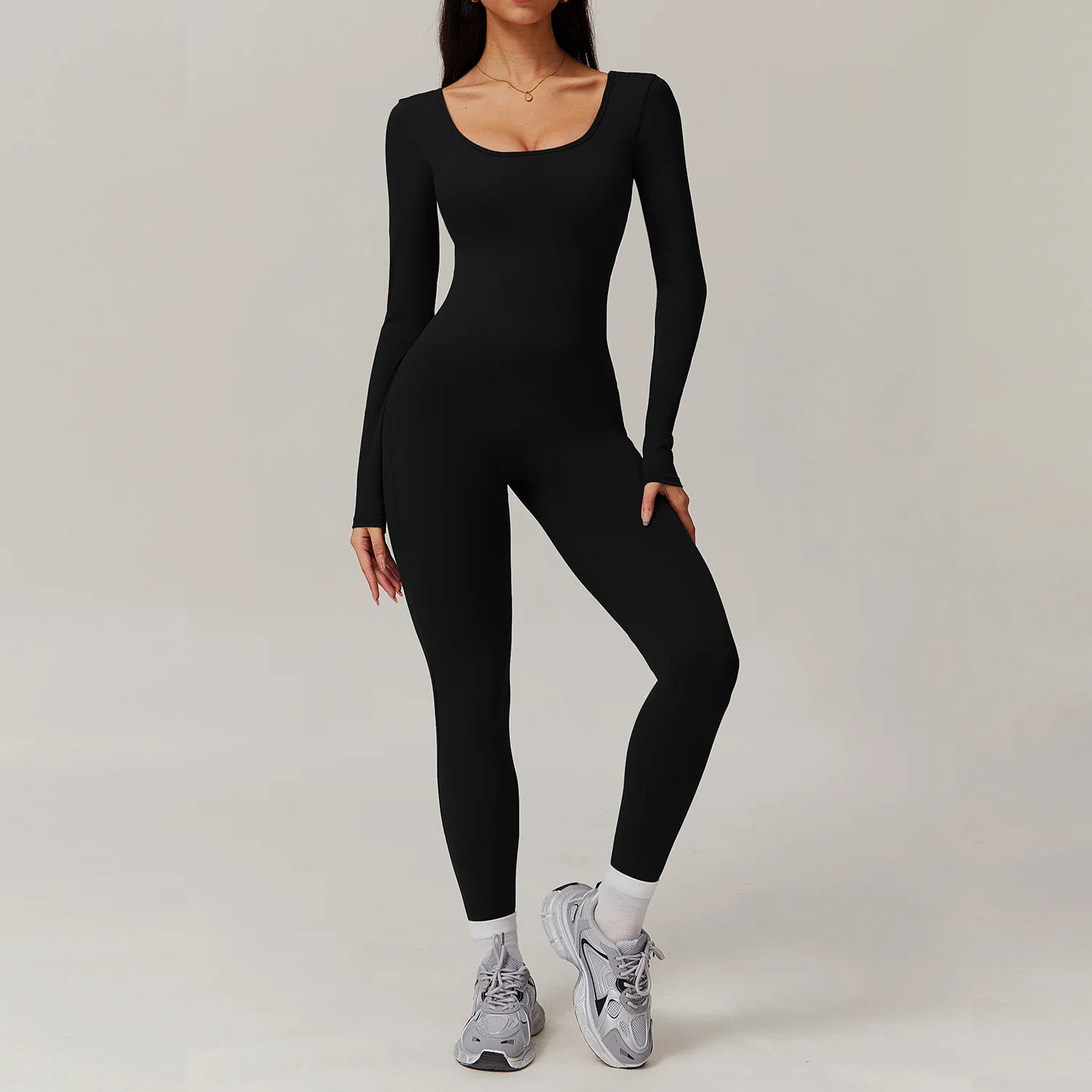 Woman wearing black open-back summer jumpsuit with long sleeves and full-length legs.