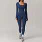 Woman wearing navy blue open-back summer jumpsuit with long sleeves and full-length legs.