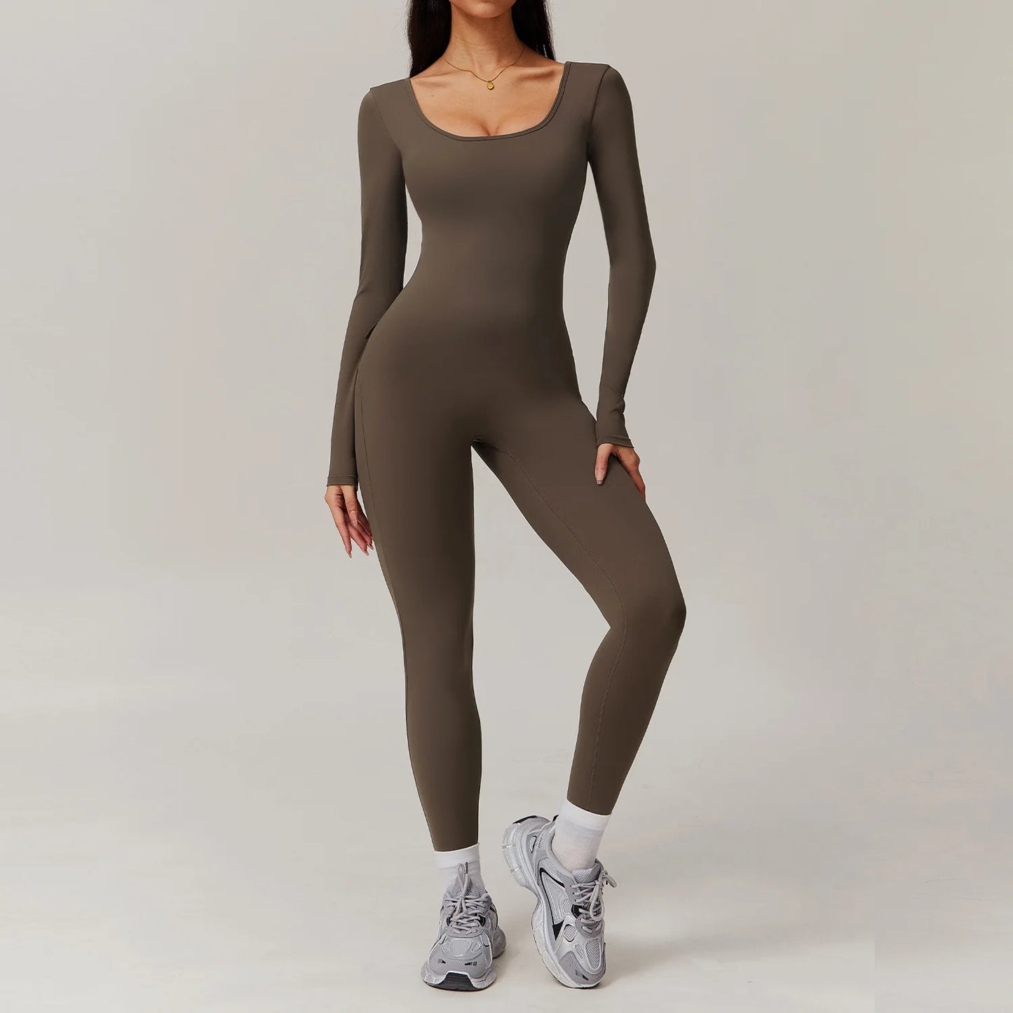 Woman wearing brown open-back summer jumpsuit with long sleeves and full-length legs.
