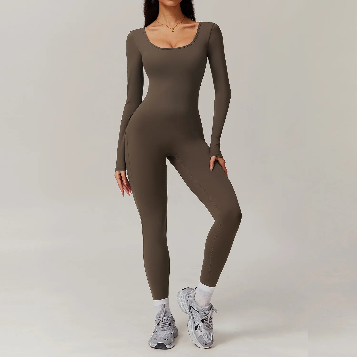 Woman wearing brown open-back summer jumpsuit with long sleeves and full-length legs.