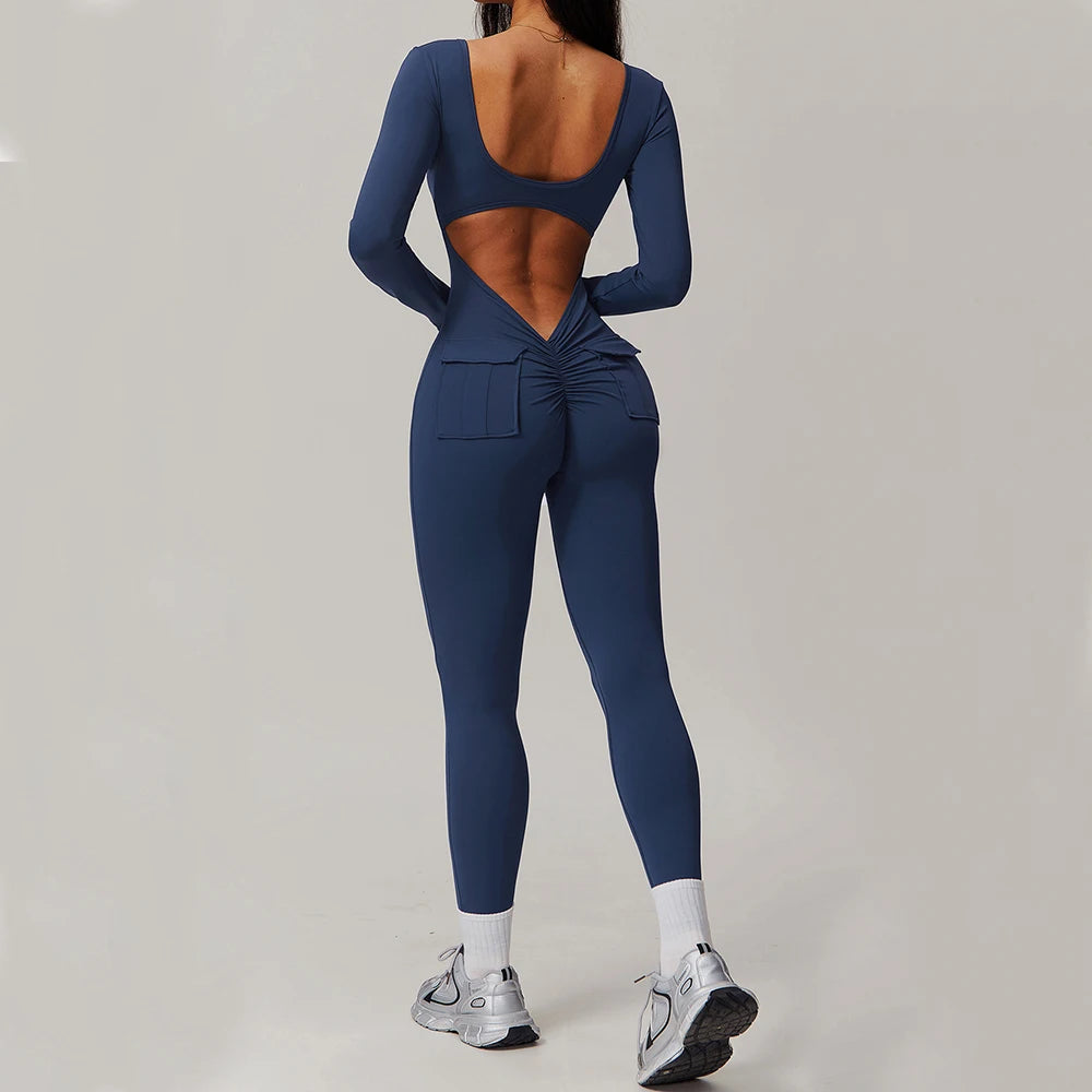 Woman wearing navy blue open-back summer jumpsuit with long sleeves and full-length legs.
