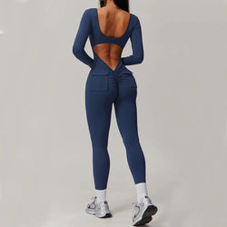 Woman wearing navy blue open-back summer jumpsuit with long sleeves and full-length legs.